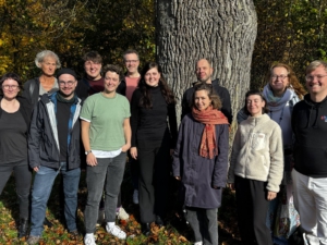 Einige Teilnehmende des Bundesvernetzungstreffens stehen in der Sonne vor einem Baum.
